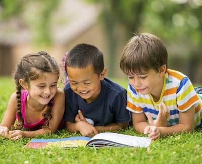 3 children reading outside